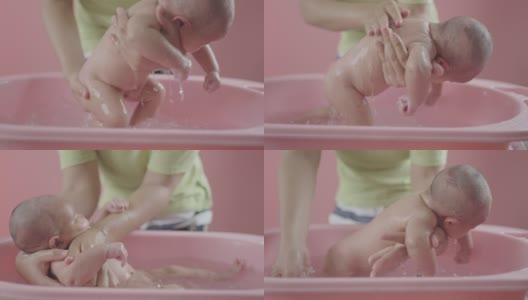 母亲脱衣服洗澡，她儿子孤立的粉红色背景。高清在线视频素材下载