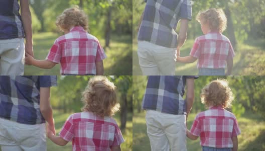 红发卷发的小男孩牵着弟弟的手走在春天夏天公园的阳光下。后视镜快乐的白人儿童散步与兄弟姐妹在阳光户外享受周末。高清在线视频素材下载