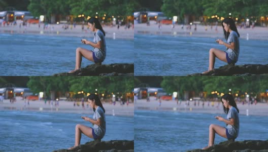 亚洲年轻女子在海滩上拿着手机高清在线视频素材下载