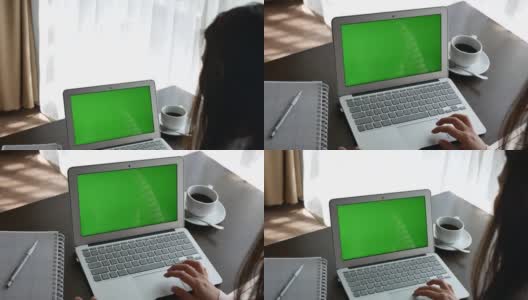 一个女人在家里看着绿色屏幕的笔记本电脑高清在线视频素材下载