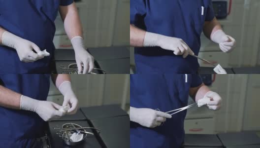 戴无菌手套的男医生在手术前从包装袋中取出医用纸巾并插入钳夹。在没有病人的诊所和医院里，用医疗器械和设备拉近外科医生的手高清在线视频素材下载