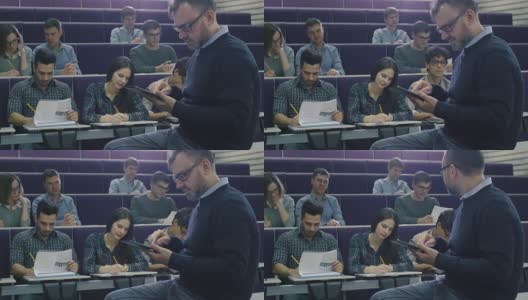 一位大学教授正在给一群来自不同民族的学生上课，他正在检查一台平板电脑。高清在线视频素材下载