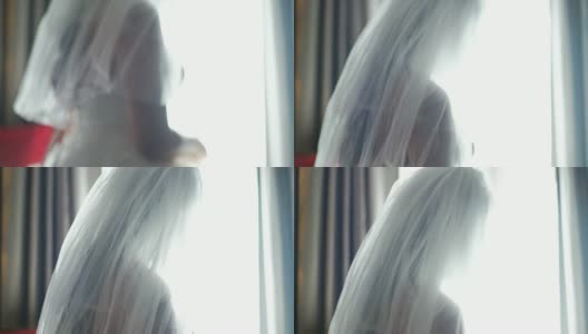 美丽的新娘在室内的窗户前戴着面纱。高清在线视频素材下载