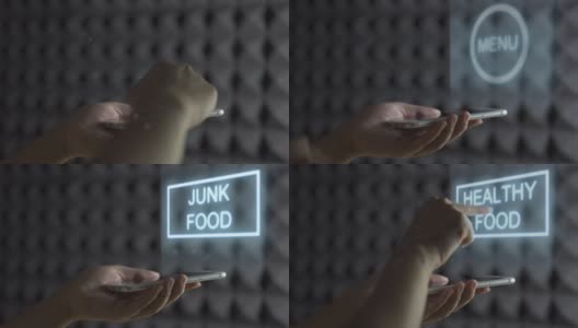人类的手握智能手机屏幕显示全息图，并滑动改变菜单垃圾食品为健康食品。食物改变全息图高清在线视频素材下载