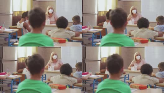 新冠肺炎疫情期间，女教师和学生在教室佩戴防护口罩高清在线视频素材下载