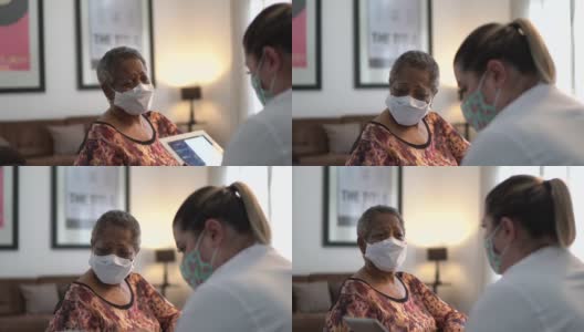 医生在老年妇女病人家中与她交谈-使用口罩高清在线视频素材下载