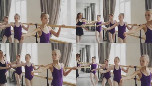 可爱的小女孩们正在上编舞课，在芭蕾舞吧做练习，而他们的老师正在帮助他们纠正手的位置，并与他们交谈。高清在线视频素材下载