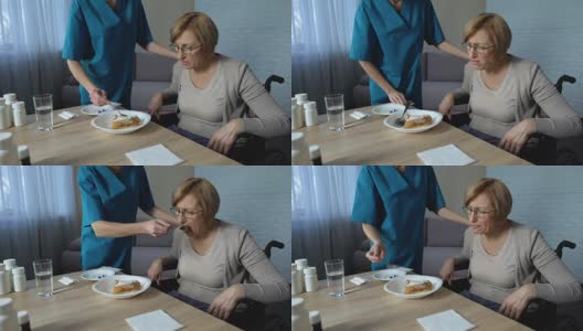 女护士帮助残疾老太太吃饭，医疗支持和照顾，悲伤高清在线视频素材下载