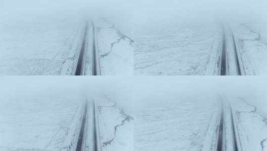 无人机拍摄的是一辆汽车在空旷的雪地里行驶在高速公路上的画面高清在线视频素材下载