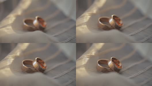 两个金色的结婚戒指躺在白灰色的表面上，在近距离的微距下闪闪发光高清在线视频素材下载
