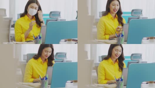 年轻快乐的亚洲商务女性穿着黄色衬衫，与她的业务团队在现代办公室或联合办公空间进行在线视频电话会议高清在线视频素材下载