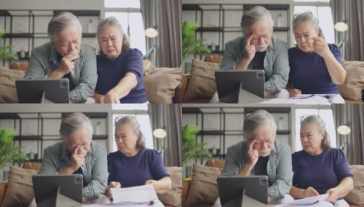 退休的亚洲老夫妇在沙发上一起检查和计算财务账单，参与财务文书工作，在客厅用电子银行笔记本电脑在线纳税高清在线视频素材下载