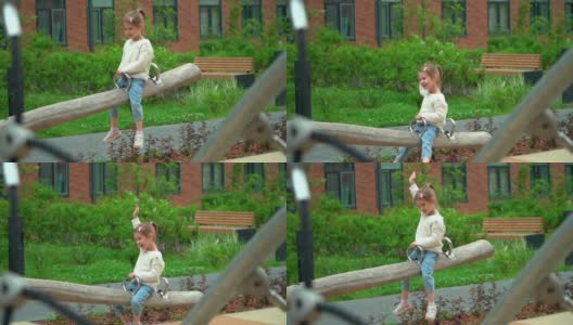 微笑的小女孩在户外的操场上荡秋千。快乐的孩子在绿色的夏日公园玩耍。儿童的休闲概念和活跃的游戏高清在线视频素材下载