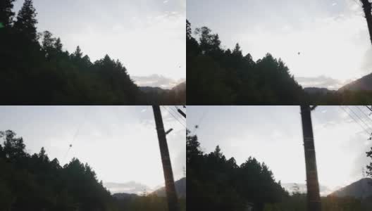 在日本高速公路上，透过车窗的树木和山脉的阴影，落日高清在线视频素材下载
