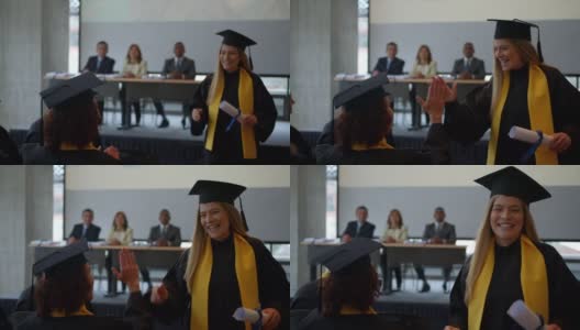 毕业典礼上，快乐的毕业生在拿到毕业证后向朋友击掌庆祝高清在线视频素材下载