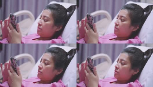 亚洲病人妇女使用触摸屏智能手机设备在医院的床上。高清在线视频素材下载