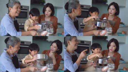 年轻的亚洲男孩在家里与母亲和祖母学习烘焙高清在线视频素材下载