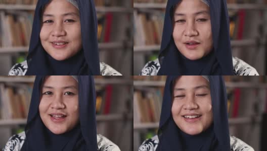 年轻的亚洲穆斯林女子站在图书馆里对着镜头说话，商人在做视频会议高清在线视频素材下载