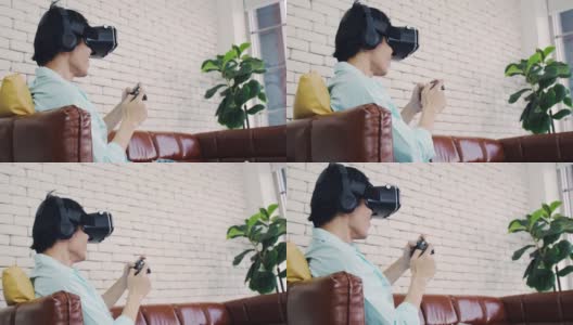 一个戴着虚拟现实眼镜的男人在现代家庭体验创新技术，一个帅气的男人在阳光明媚的日子用VR眼镜玩游戏。高清在线视频素材下载