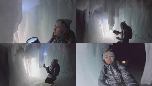 贝加尔湖冰洞上的女游客。观点认为有问题。女孩背包客正在冰洞中行走。游客看着美丽的冰洞。徒步旅行者穿银色夹克，背包，led灯。高清在线视频素材下载