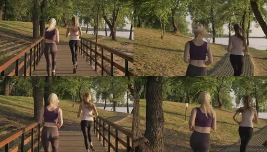 两个年轻漂亮的女跑步者在公园对面的桥上慢跑，减肥，健身模特跑步，从后面看高清在线视频素材下载