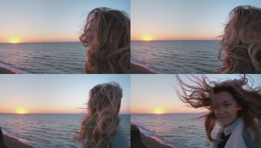 美丽的白种人卷发年轻女子日出或日落在海洋。风吹长了头发。她呼吸着海边的空气。自由的概念，生活的享受。慢动作高清在线视频素材下载