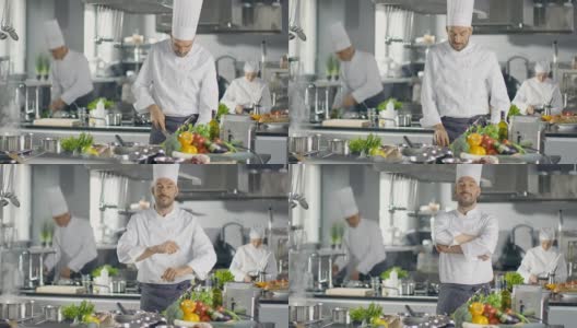 一家大餐厅的著名厨师在现代厨房里双臂交叉微笑。他的幕后工作人员。高清在线视频素材下载