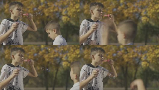 男孩在公园里吹肥皂泡。孩子的手在捏肥皂泡。缓慢的运动。高清在线视频素材下载