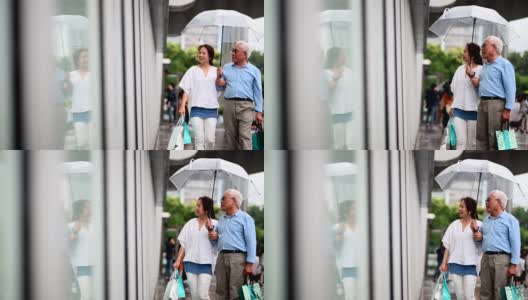 一对老年夫妇在雨季的时候逛街高清在线视频素材下载