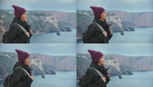 愉快的潮女人旅行背包客站在高崖顶在多风的天气享受自然高清在线视频素材下载