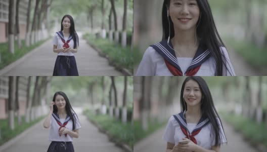 年轻的亚洲女性，戴着耳机，走在校园里高清在线视频素材下载
