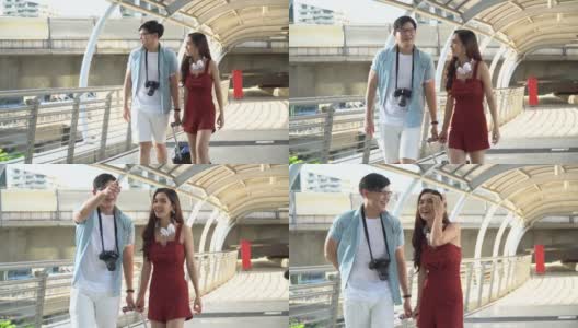 年轻的亚洲夫妇旅行者在步行和观光城市交谈行李。情人旅游者在假期外出旅游。高清在线视频素材下载