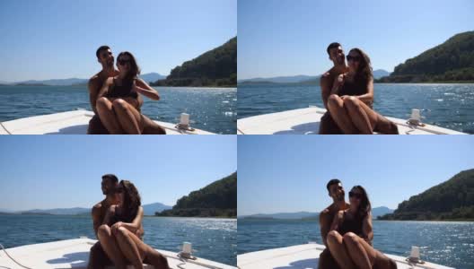 在阳光明媚的日子里，一对年轻的情侣坐在船头，对着摄影师摆姿势。幸福的情侣在船上共度时光，享受夏天的旅行。假期的概念。前视图高清在线视频素材下载