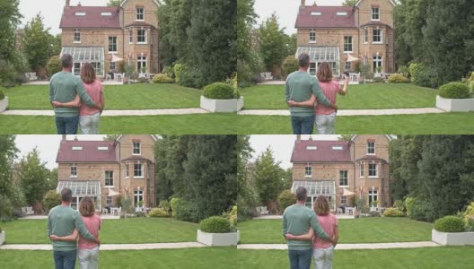 实时视频，成熟的夫妇互相拥抱，同时看他们的新房子高清在线视频素材下载
