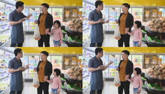 一位亚洲华人母亲和她的女儿正在和一位男店主交谈，这位男店主戴着围裙，希望得到店员的建议高清在线视频素材下载