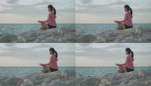 亚洲运动女性沉思坐在海边的石头日落。高清在线视频素材下载