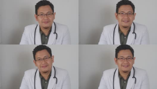 亚洲男医生对着镜头微笑，在视频通话中给出建议。在线医生远程医疗远程保健概念高清在线视频素材下载