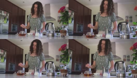 一个年轻女人在厨房里煮着一杯完美的茶高清在线视频素材下载