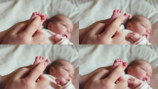 演示婴儿脚反射。妈妈按脚趾脚，手指握紧松开。高清在线视频素材下载