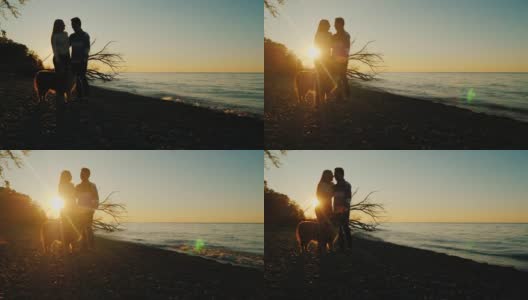 年轻夫妇在日落与宠物。肩并肩站在湖的背景和夕阳高清在线视频素材下载