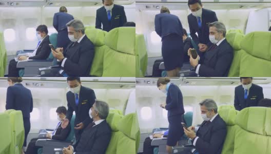 在新冠肺炎大流行期间，白人商人在飞机上戴口罩使用手机，以防止感染新冠肺炎。该男子正在等待机上乘务员提供的机上服务。高清在线视频素材下载