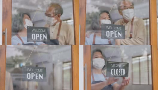 戴口罩的亚洲老年夫妇转向欢迎我们打开玻璃门上的标志，在COVID-19结束封锁和隔离后，我们重新开放家庭业务。爷爷奶奶很开心，互相拥抱。高清在线视频素材下载