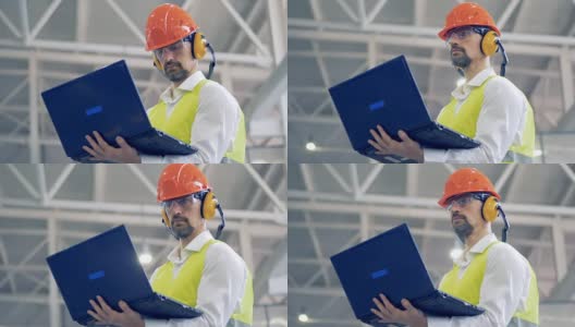一名工厂男员工正在用他的笔记本电脑工作，同时扫视四周高清在线视频素材下载