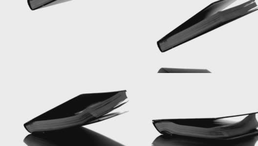 沉重的黑书落在白色的表面上高清在线视频素材下载