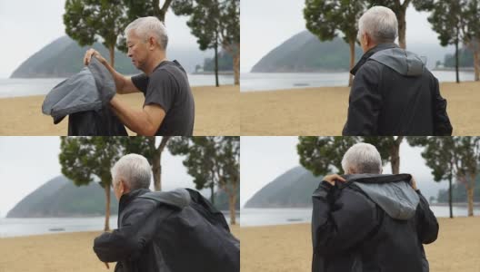 一个亚洲老人独自站在海滩前高清在线视频素材下载