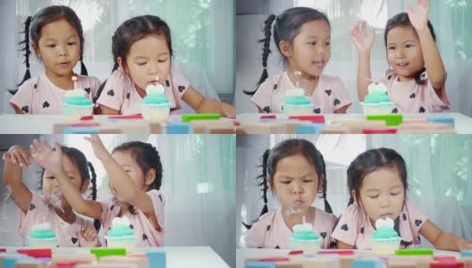 两个亚洲小女孩在家里一起吹灭生日蛋糕上的蜡烛。慢动作拍摄在工作室。高清在线视频素材下载