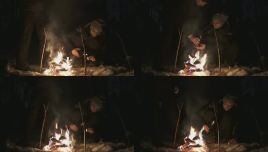 两个朋友在每年冬天的晚上在树林里生火，喝茶高清在线视频素材下载