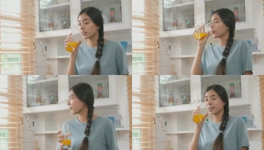 年轻美丽的亚洲女人在厨房喝橙汁的特写，健康的生活方式高清在线视频素材下载