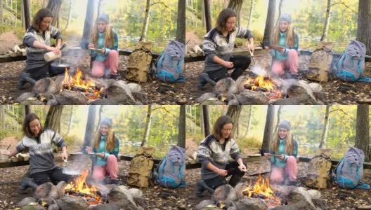 女性朋友在户外露营时在篝火上做传统煎饼高清在线视频素材下载