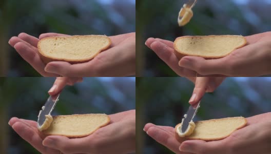 一位女性的手用一把刀在白面包上抹黄油。高清在线视频素材下载